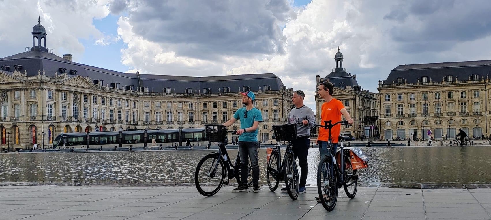 Bike tour group beside historic riverside plaza with grand buildings