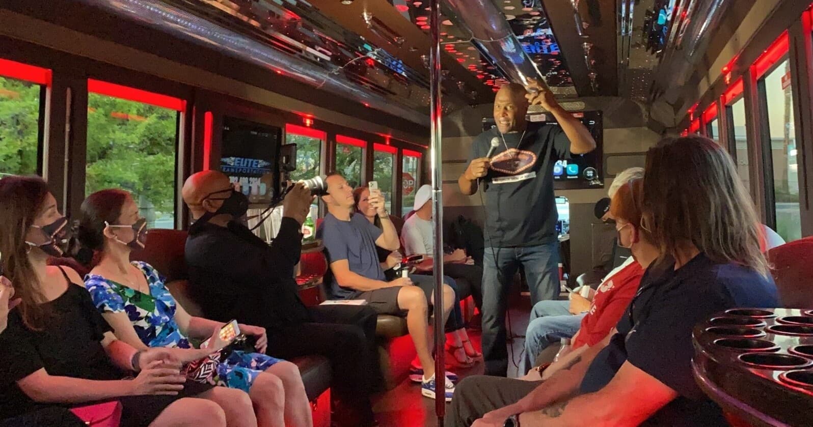 Group enjoying party bus karaoke inside lit party coach