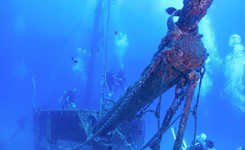 Scuba divers exploring an underwater shipwreck on Maui reef