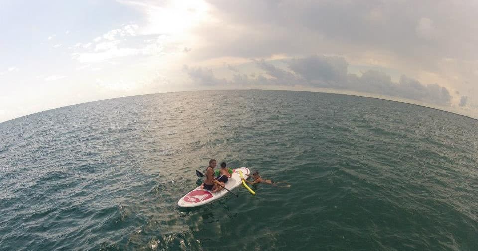 Paddleboarders in open ocean at sunset, expansive sea view