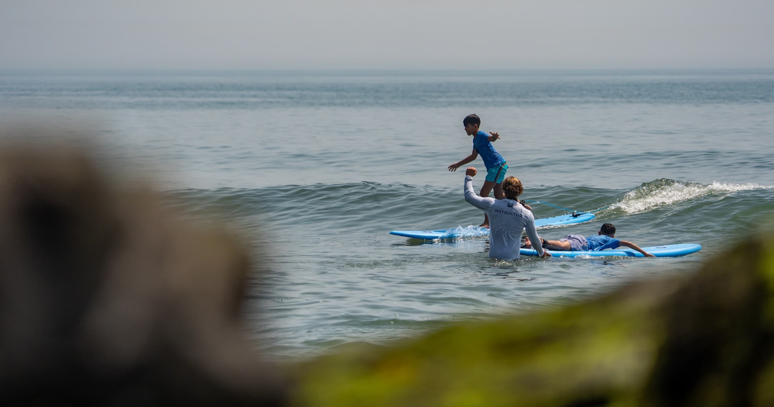 Paddleboarders balancing on calm sea near rocky shoreline