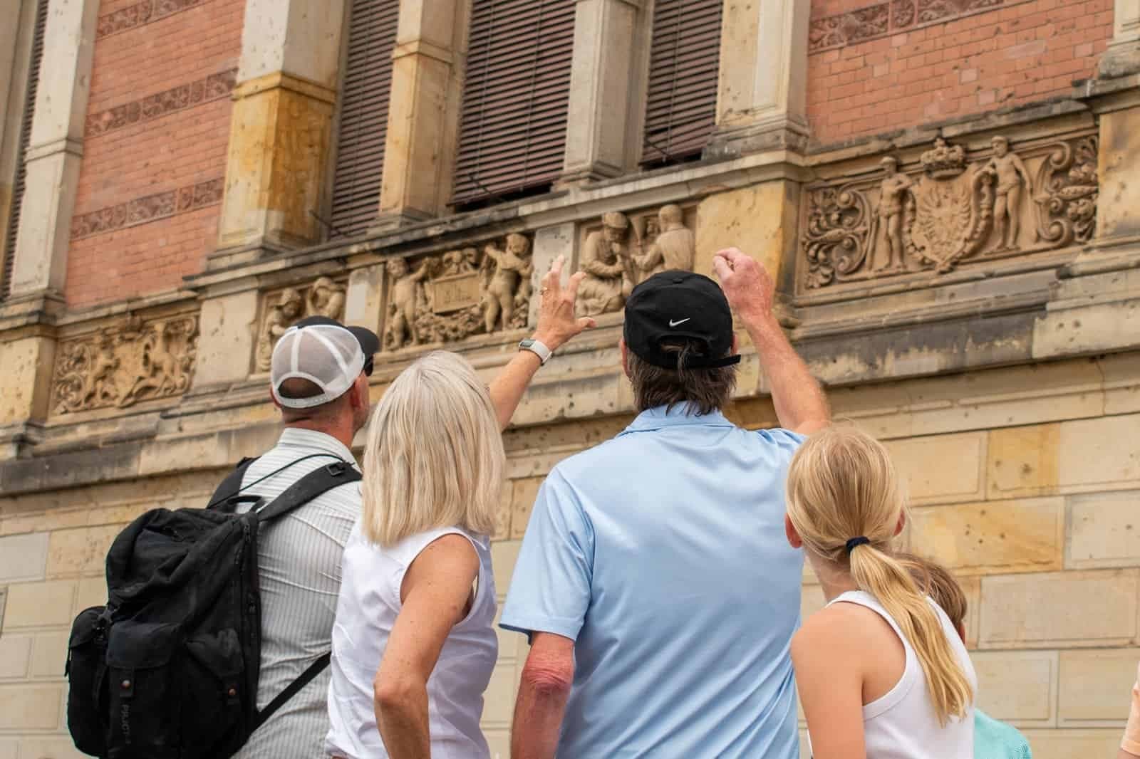 Small group examining ornate building façade on urban walking tour