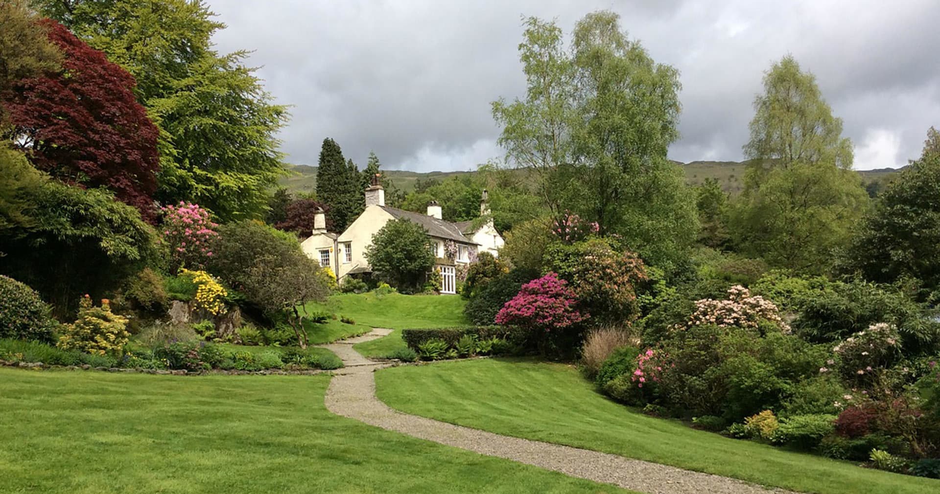 Cottage garden pathway with manicured lawns and blooming shrubs