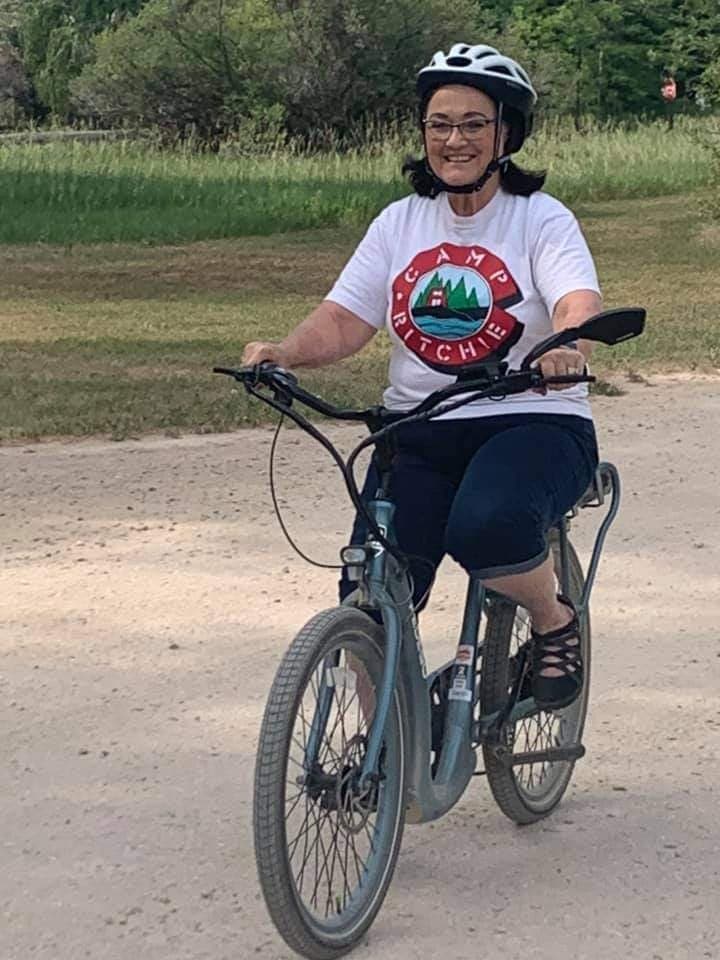 Woman riding e-bike on dusty trail through grassy parkland
