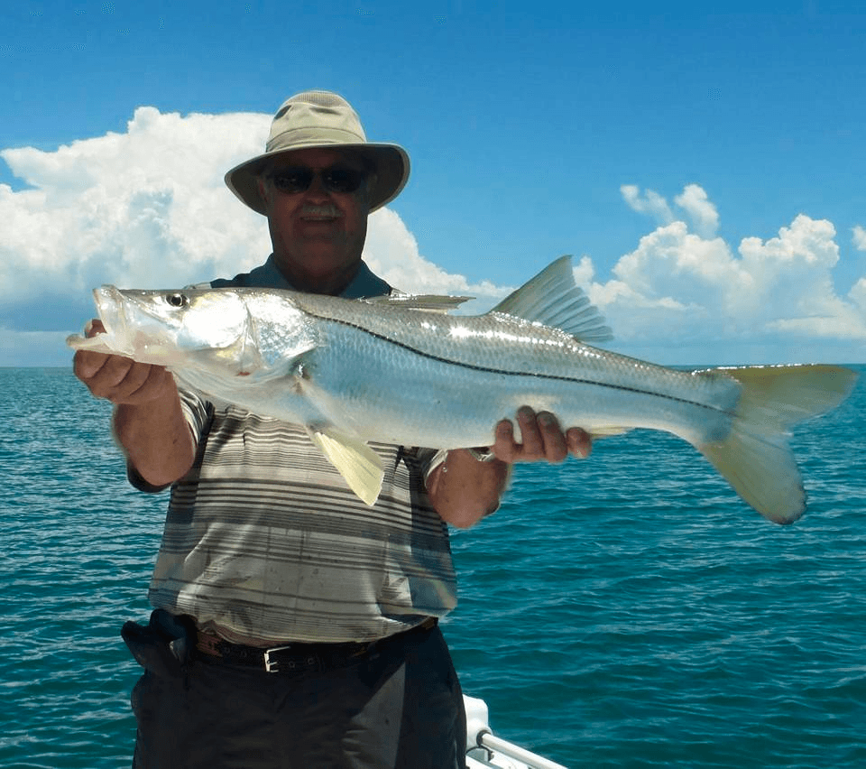 Angler holding large snook on boat in open blue ocean