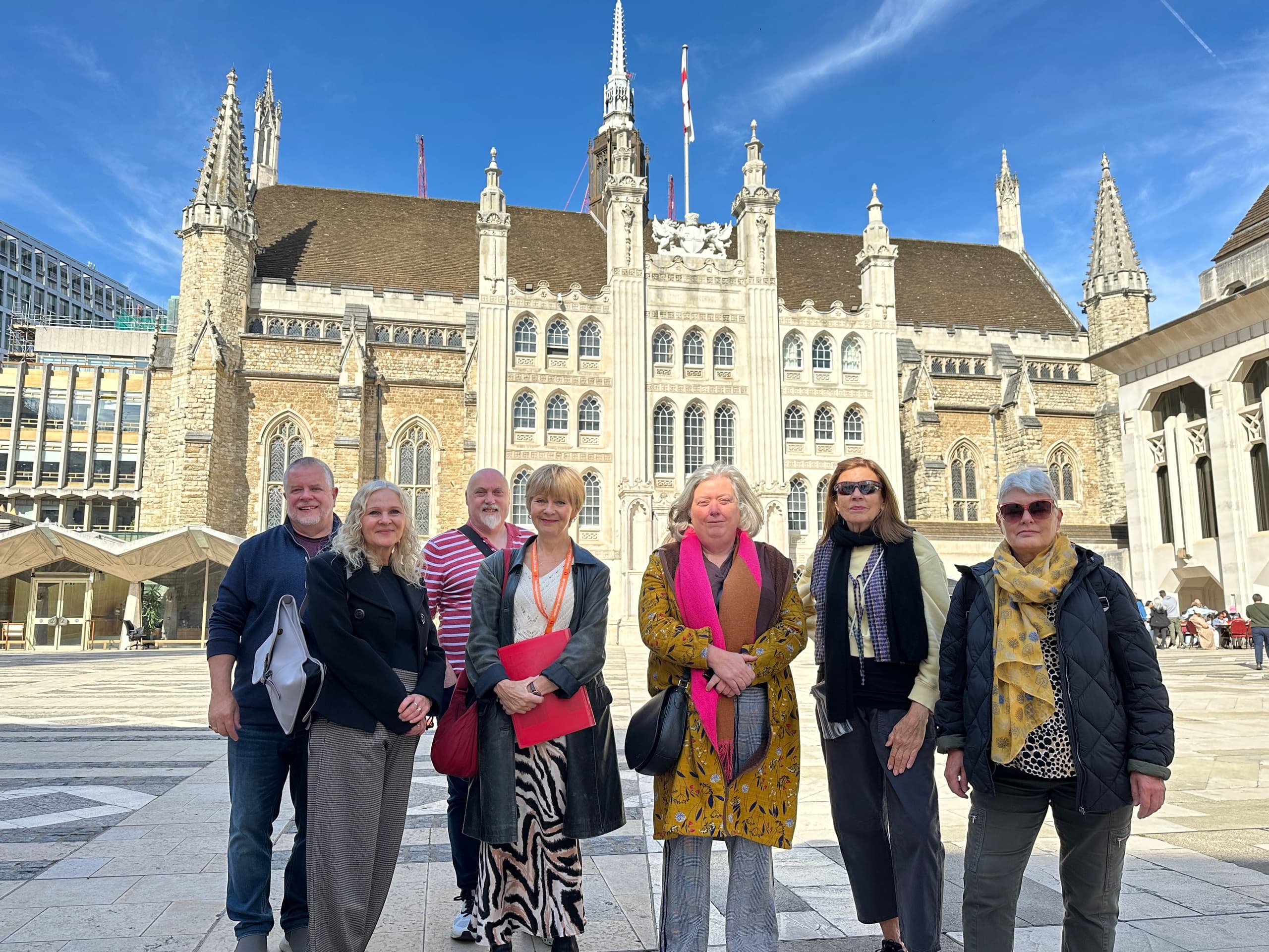 Tour group outside grand London landmark listening to guide