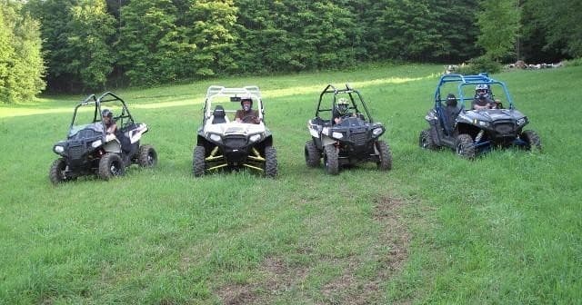 Four UTVs parked in grassy field, group off-road adventure staging