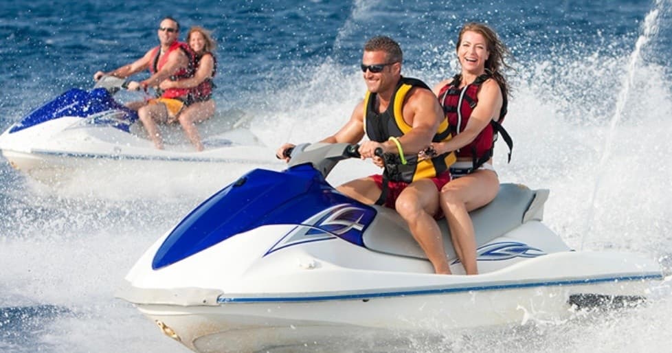 Two people riding a jet ski on sunny ocean waves
