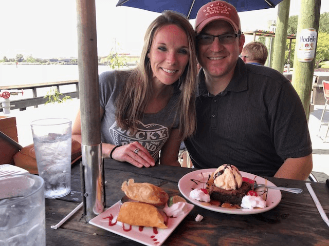 Couple enjoying waterfront outdoor dining at a sunny pier