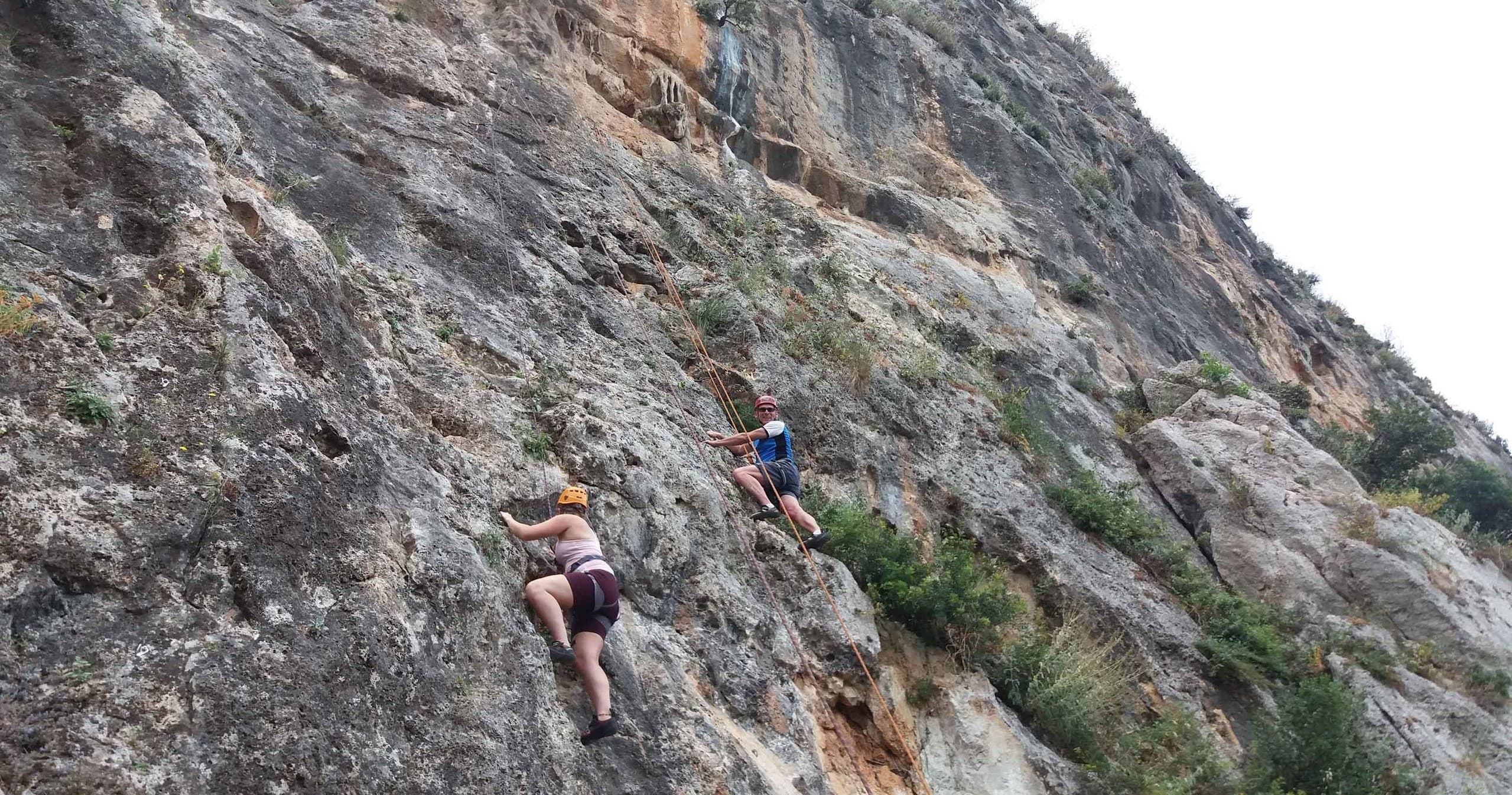 Two climbers scaling steep rock face on rugged outdoor route