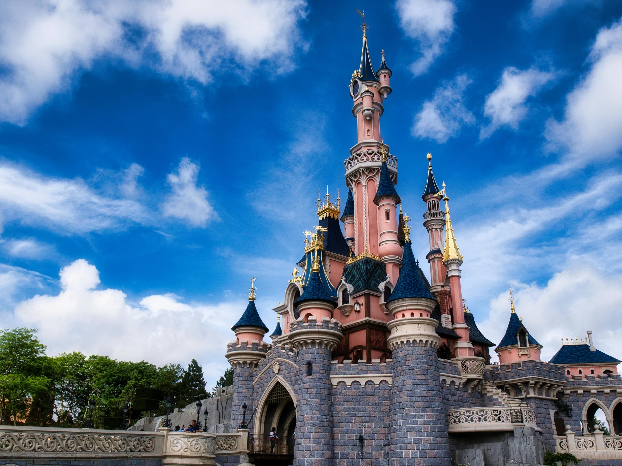 Fairytale castle at theme park with vibrant sky, family visit