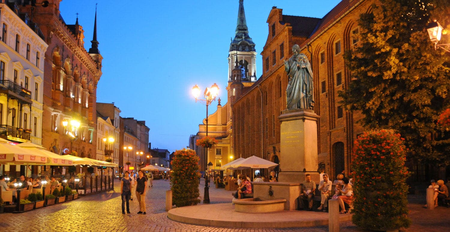 Evening cobblestone street with outdoor cafes and warm lights
