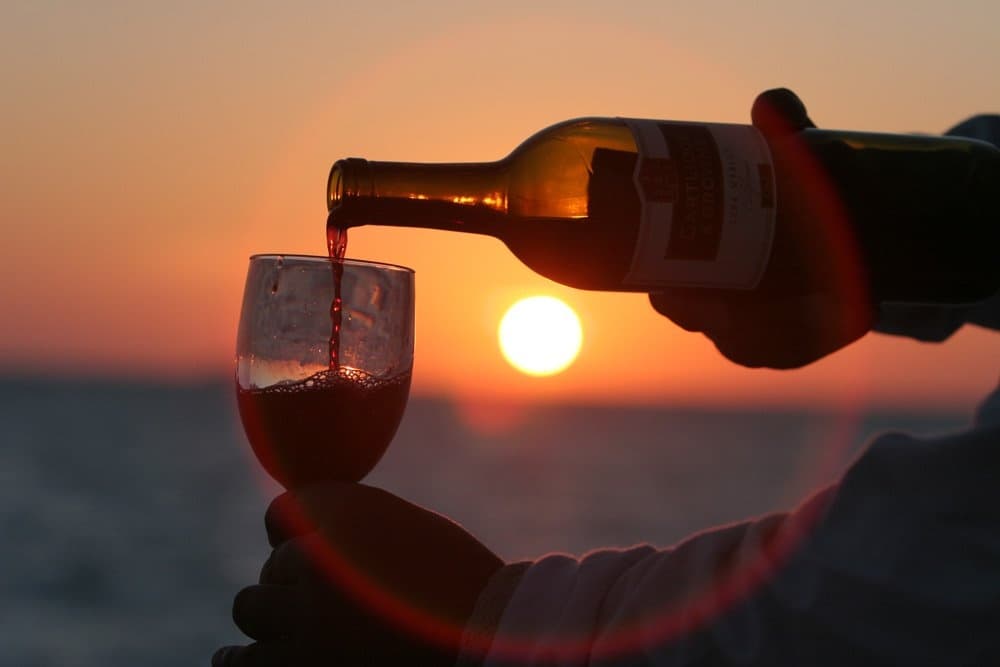 Sunset wine pouring over sea view for coastal Greek tasting