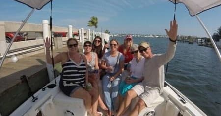 Friends on charter boat cruising coastal marina, smiling and waving