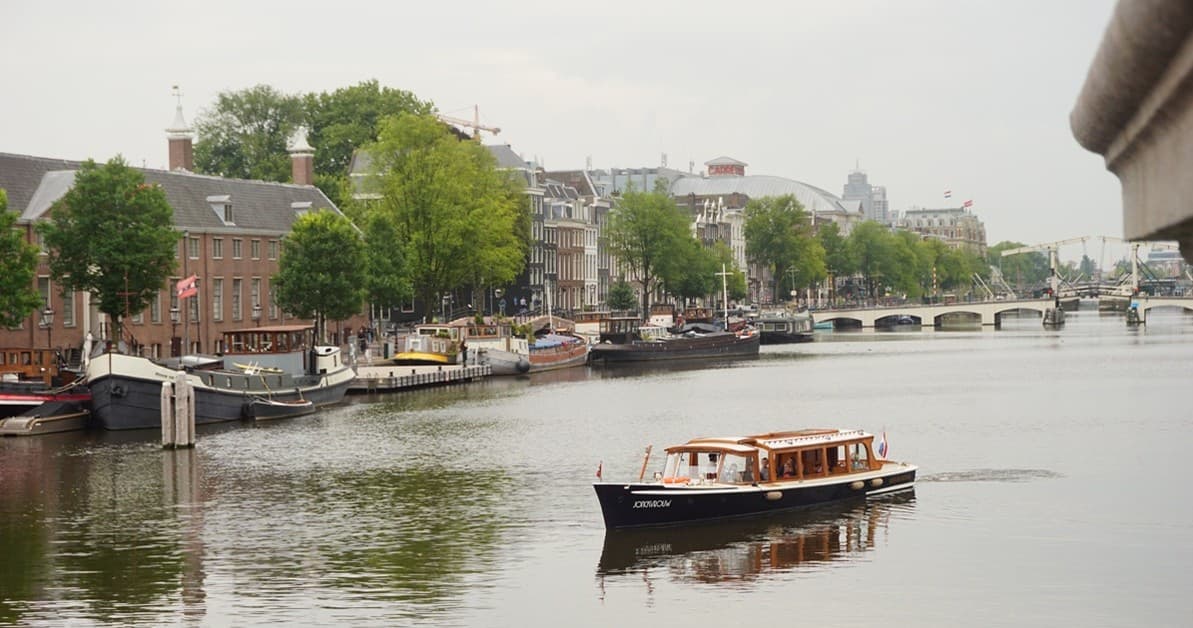 Sunset canal cruise over Amsterdam skyline with golden light