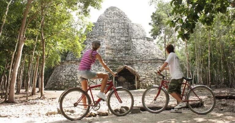 Couple on bicycles exploring Mayan ruins in jungle eco bike tour