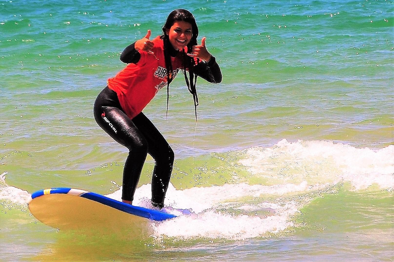 Woman surfing small wave in clear green ocean near shore