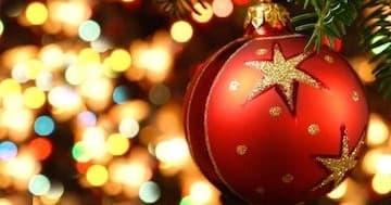 Red Christmas ornament hanging with warm bokeh lights indoor scene