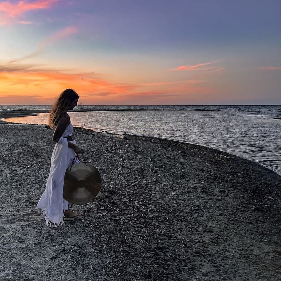 Woman walking along shoreline at sunset on a scenic beach