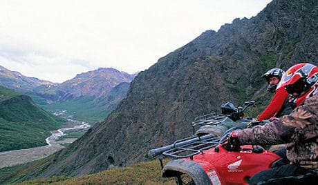 ATV riders on ridge overlooking Alaskan mountain valley
