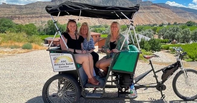 Palisade pedicab ride with passengers against Colorado canyon