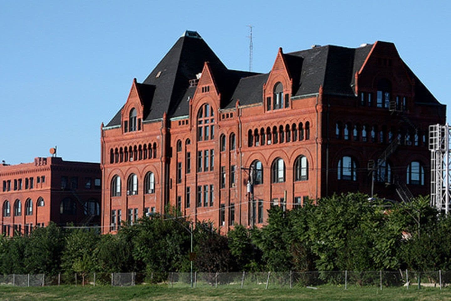 Historic red brick urban building beside green lawn, daytime