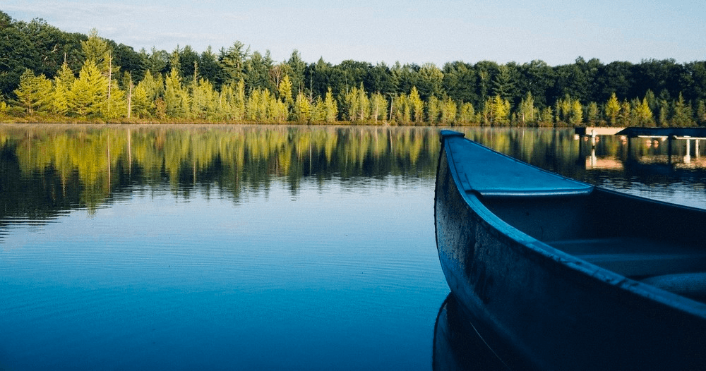 Canoe moored on a calm reflective alpine lake at sunrise
