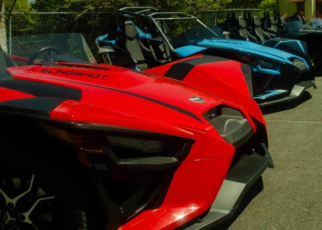 Red Slingshot parked in lot with other vehicles, urban setting