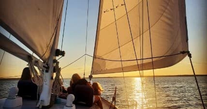 Sunset sailing with crew under warm golden light on deck