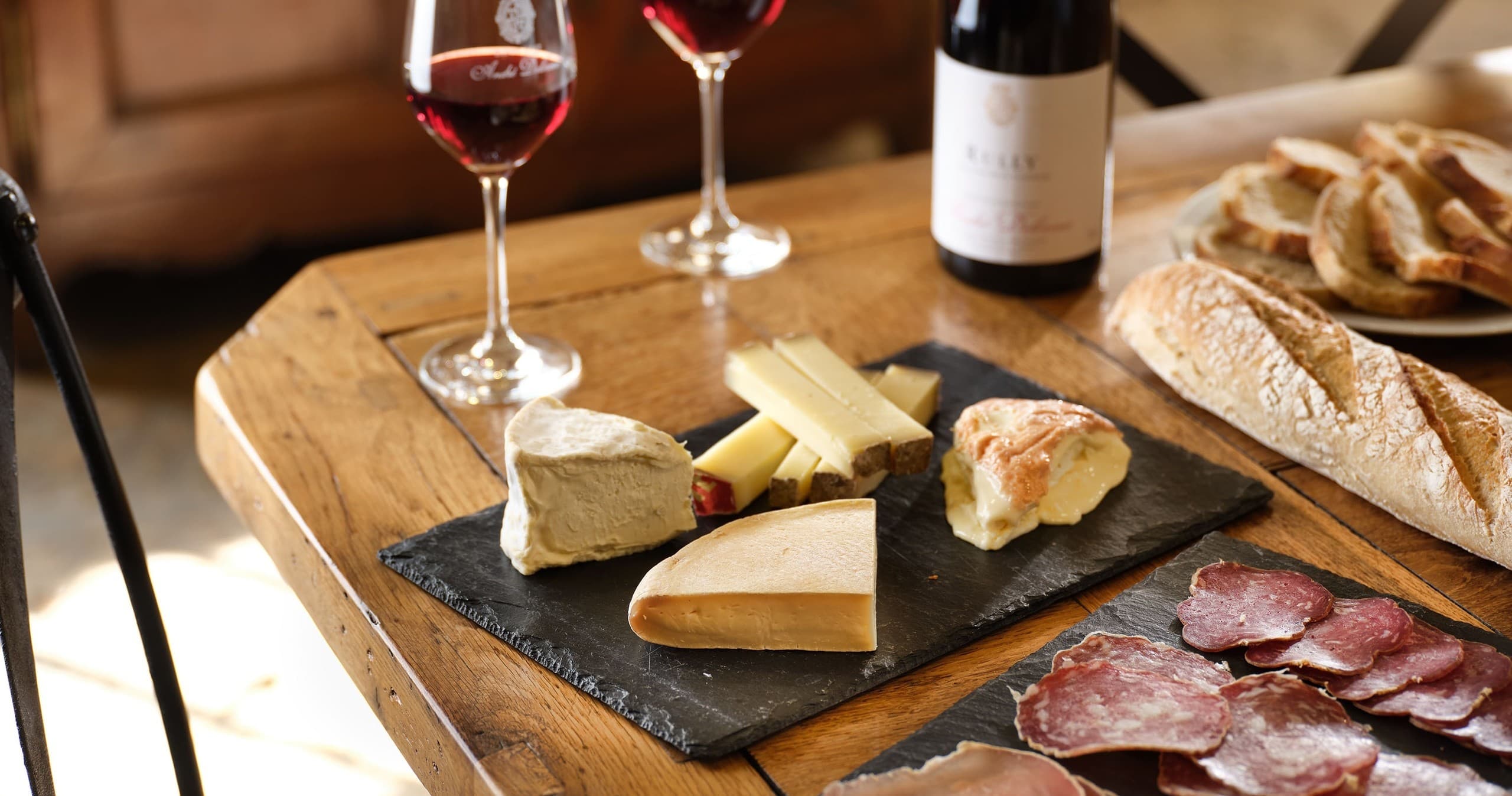 Cheese and charcuterie board with wine glasses at tasting table