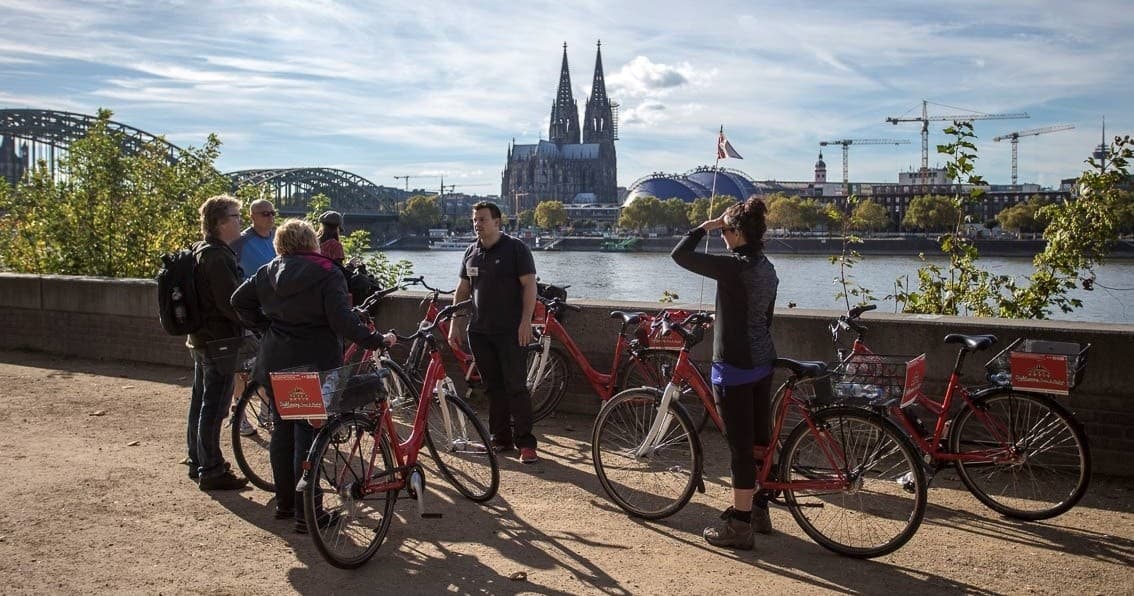 Cyclists enjoying riverside path with Cologne Cathedral view