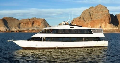 Luxury cruise boat on Lake Powell waters with red rock shoreline