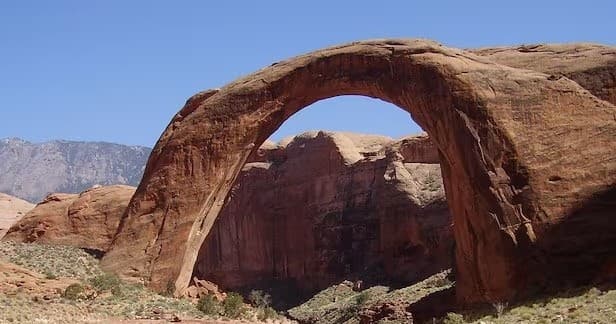 Sightseers viewing natural sandstone arch in Lake Powell canyon