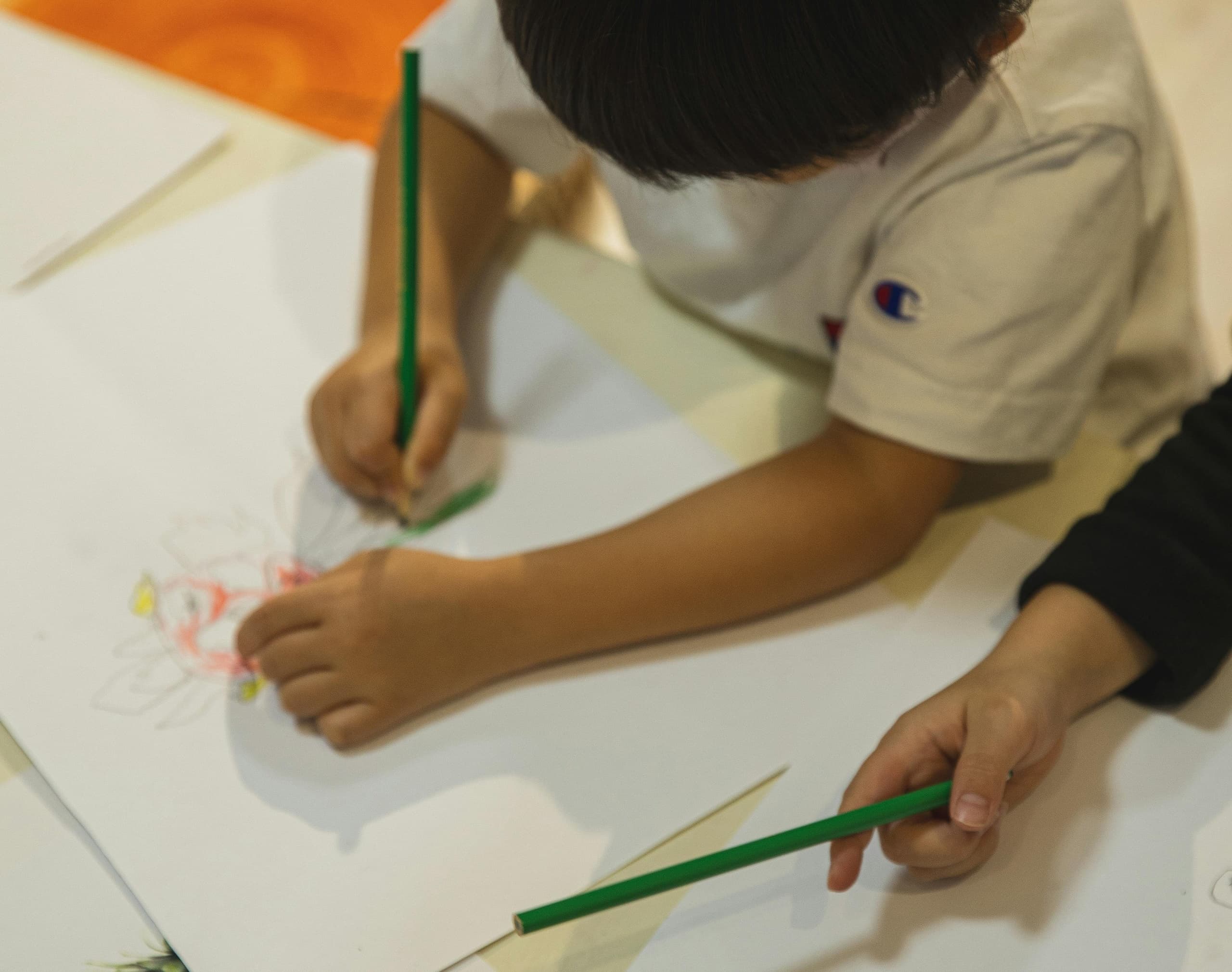 Children drawing with colored pencils in indoor art studio activity
