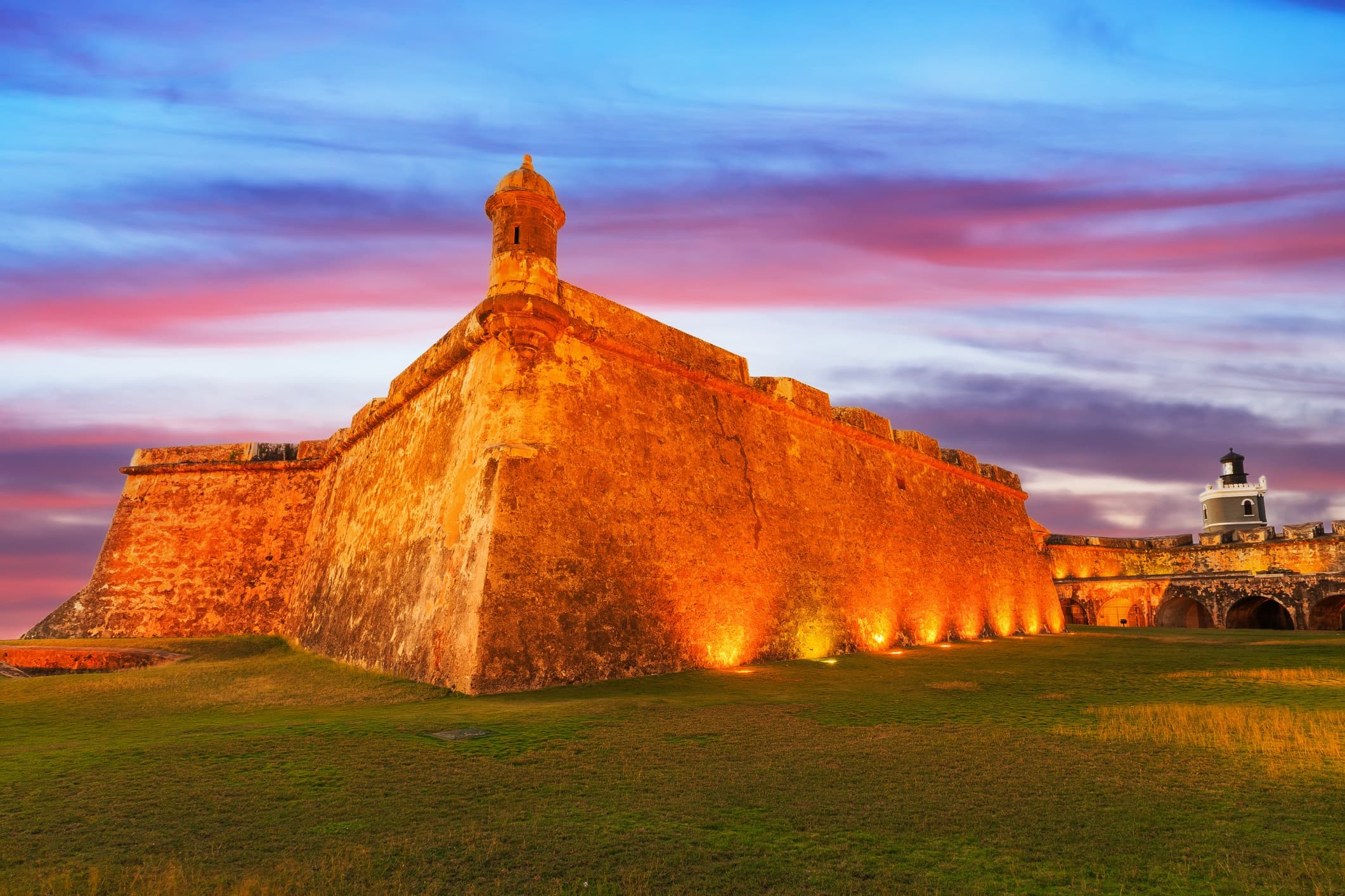 Fortress on grassy coastal hill lit at sunset for coastal tours
