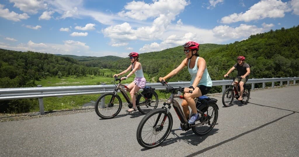 Cyclists pedaling along scenic Vermont road with rolling hills