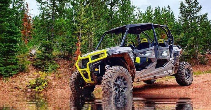 UTV side-by-side traversing forest mud trail outdoors
