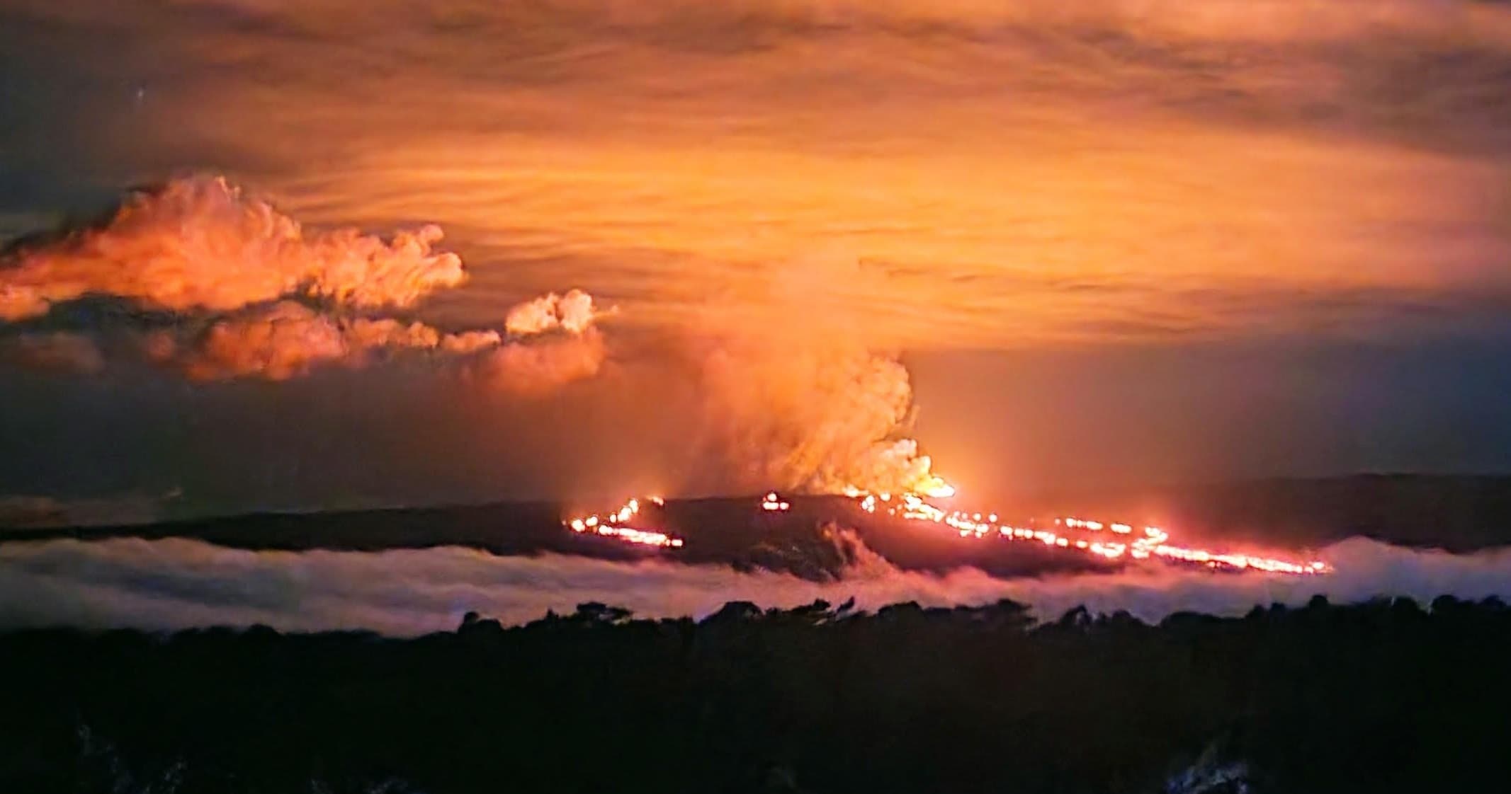 Night lava flow and volcanic eruption lighting sky with glow