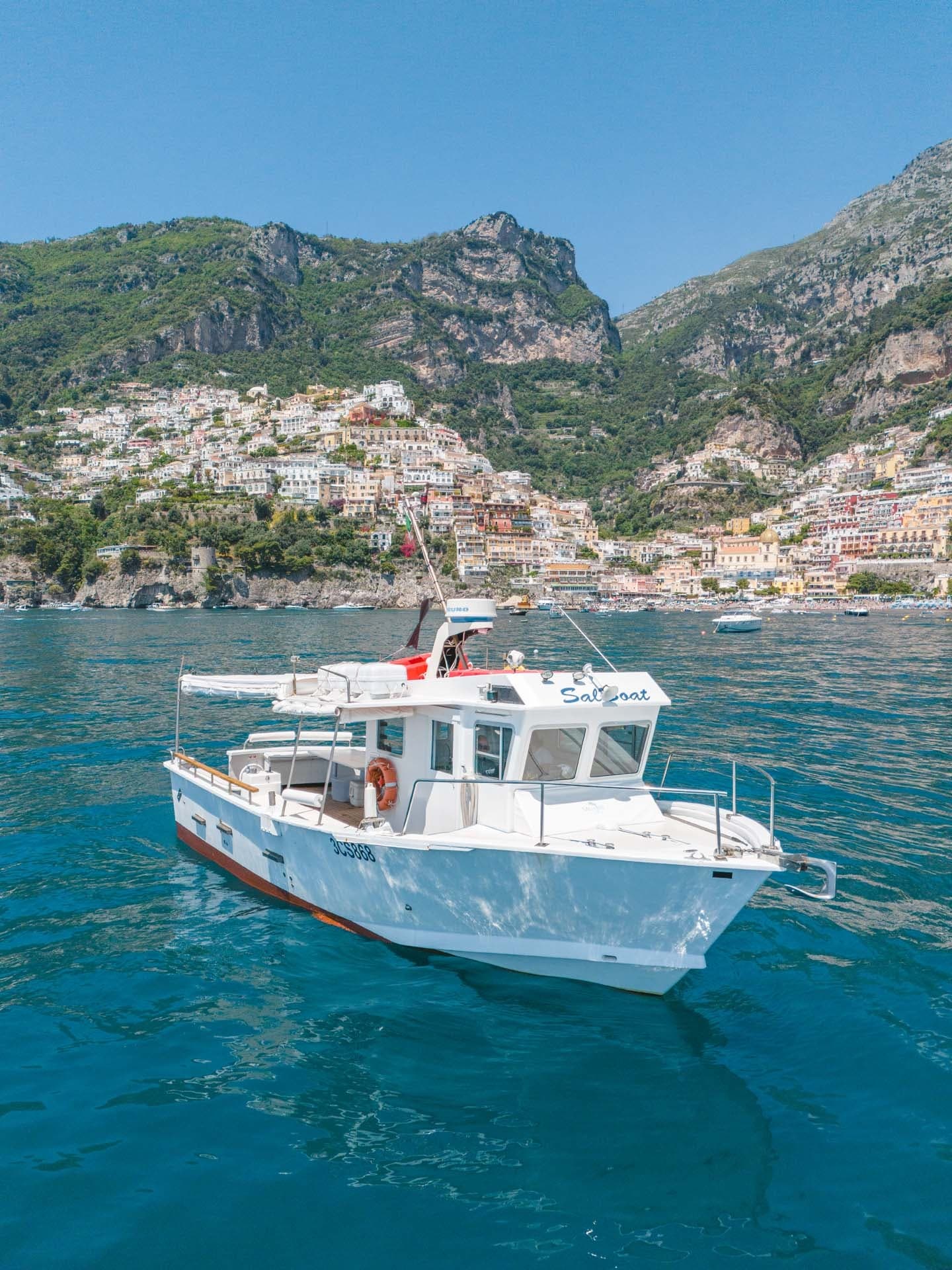 Private motorboat anchored near Positano shoreline, clear blue sea