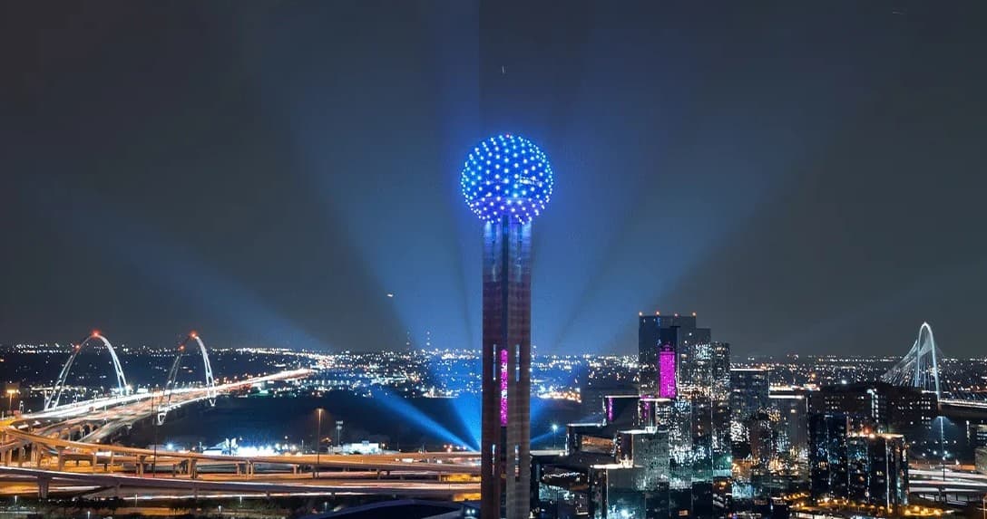 Illuminated Reunion Tower overlooking Dallas skyline at night