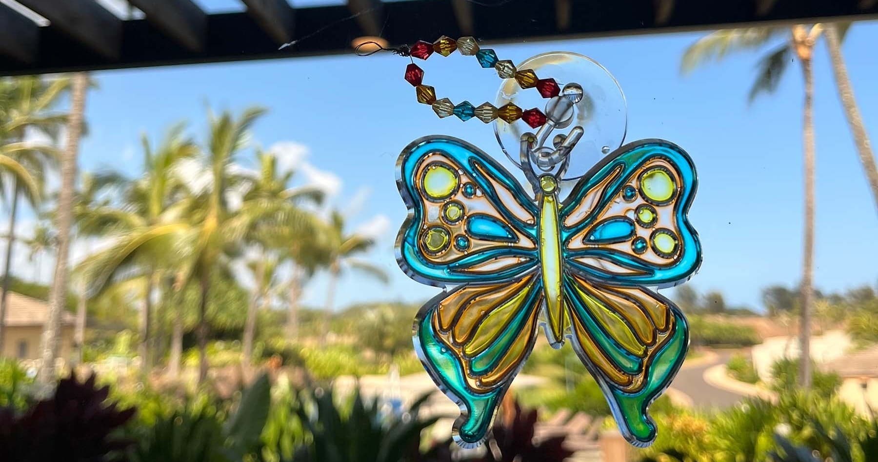 Decorative butterfly suncatcher with palm trees and resort view