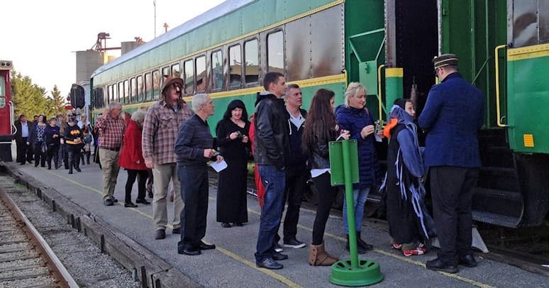 Passengers boarding vintage green railcar at station platform