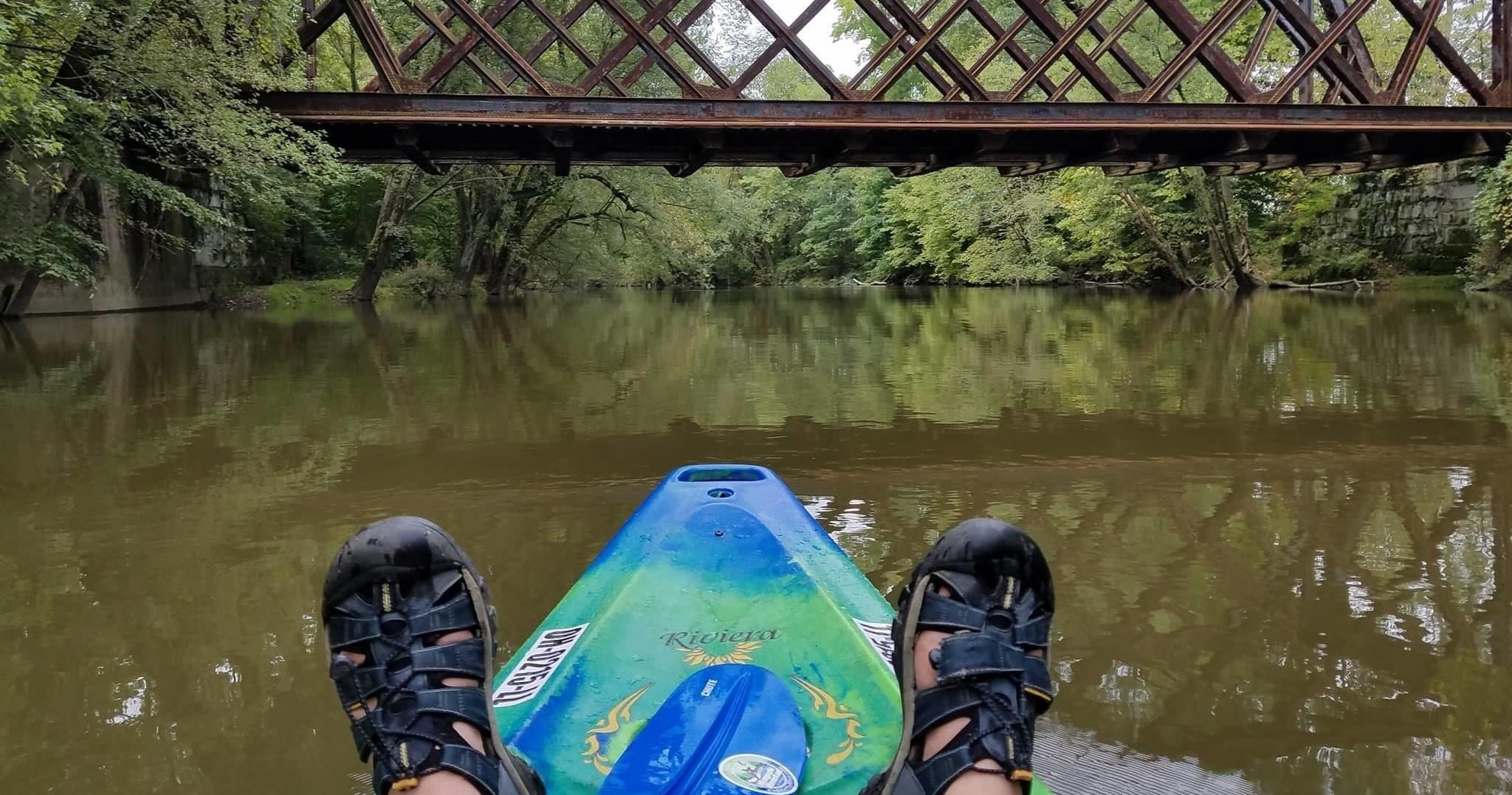 POV kayak view under an iron bridge on a slow river float
