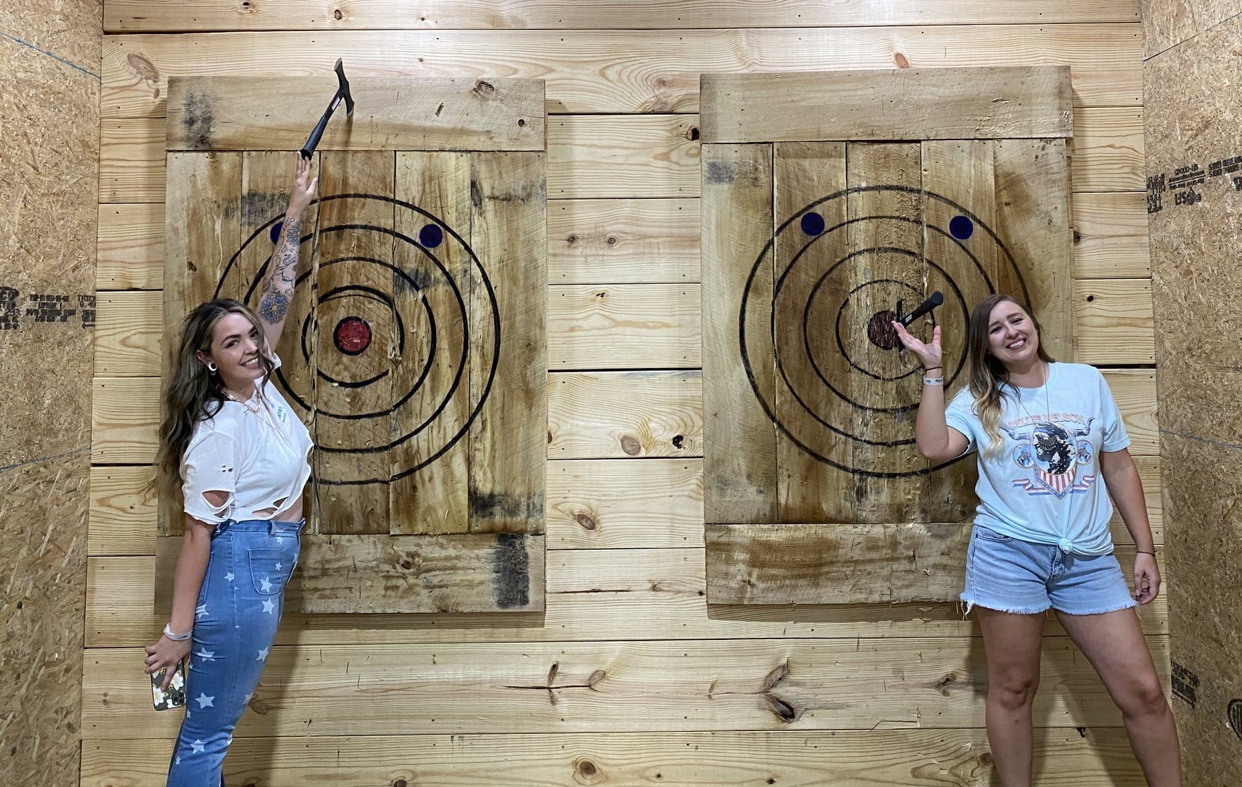 Two women celebrating successful throws at indoor axe-throwing