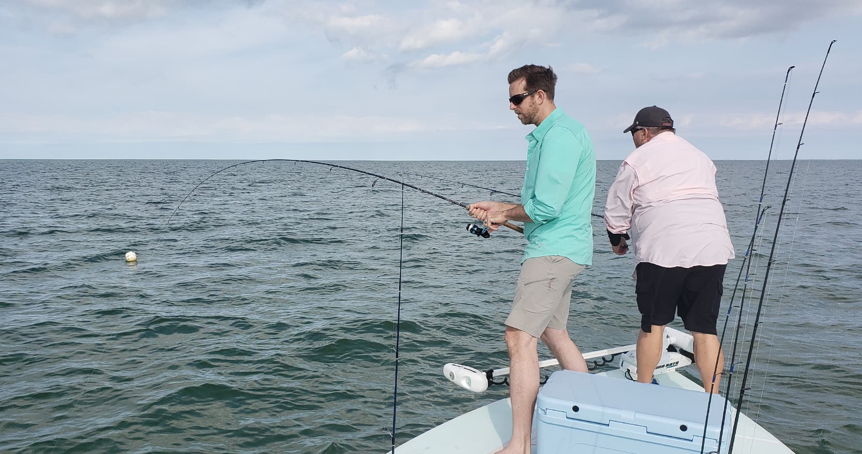 Two anglers fishing from a flats boat on open coastal waters