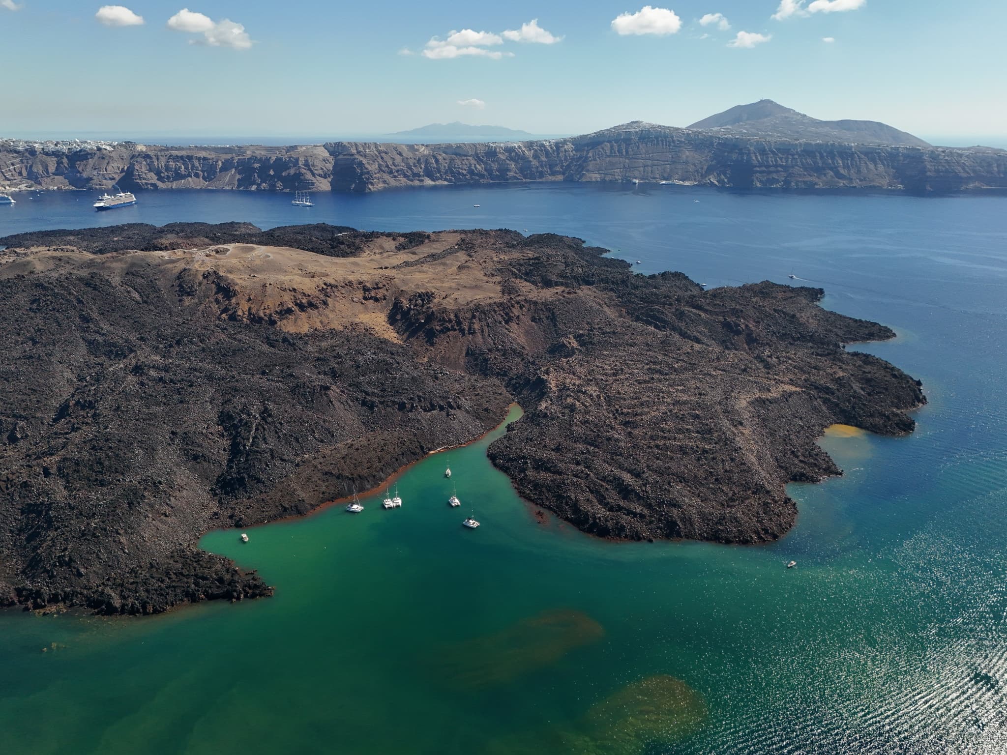 Aerial view of Santorini caldera and volcanic islets with anchored boats