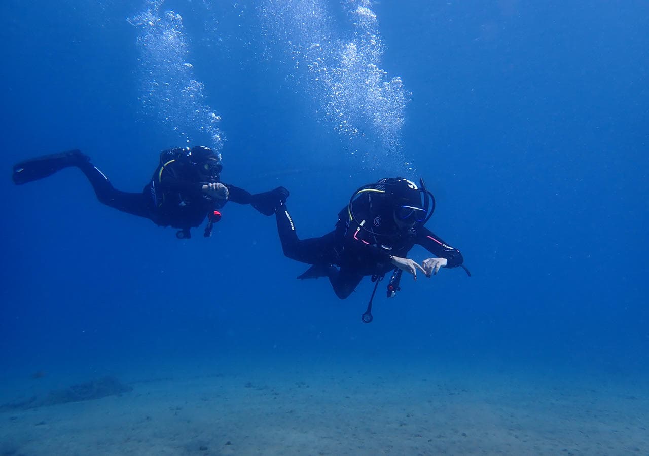 Scuba diver silhouette ascending through sunlit blue water