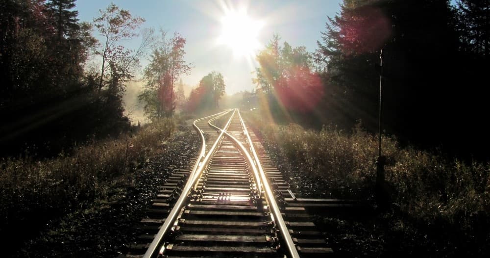 Sunlit railroad tracks leading through autumn forest in Adirondacks