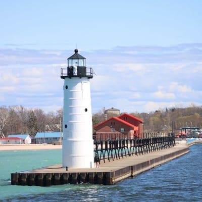 White lighthouse with pier at Ludington harbor, scenic shoreline view