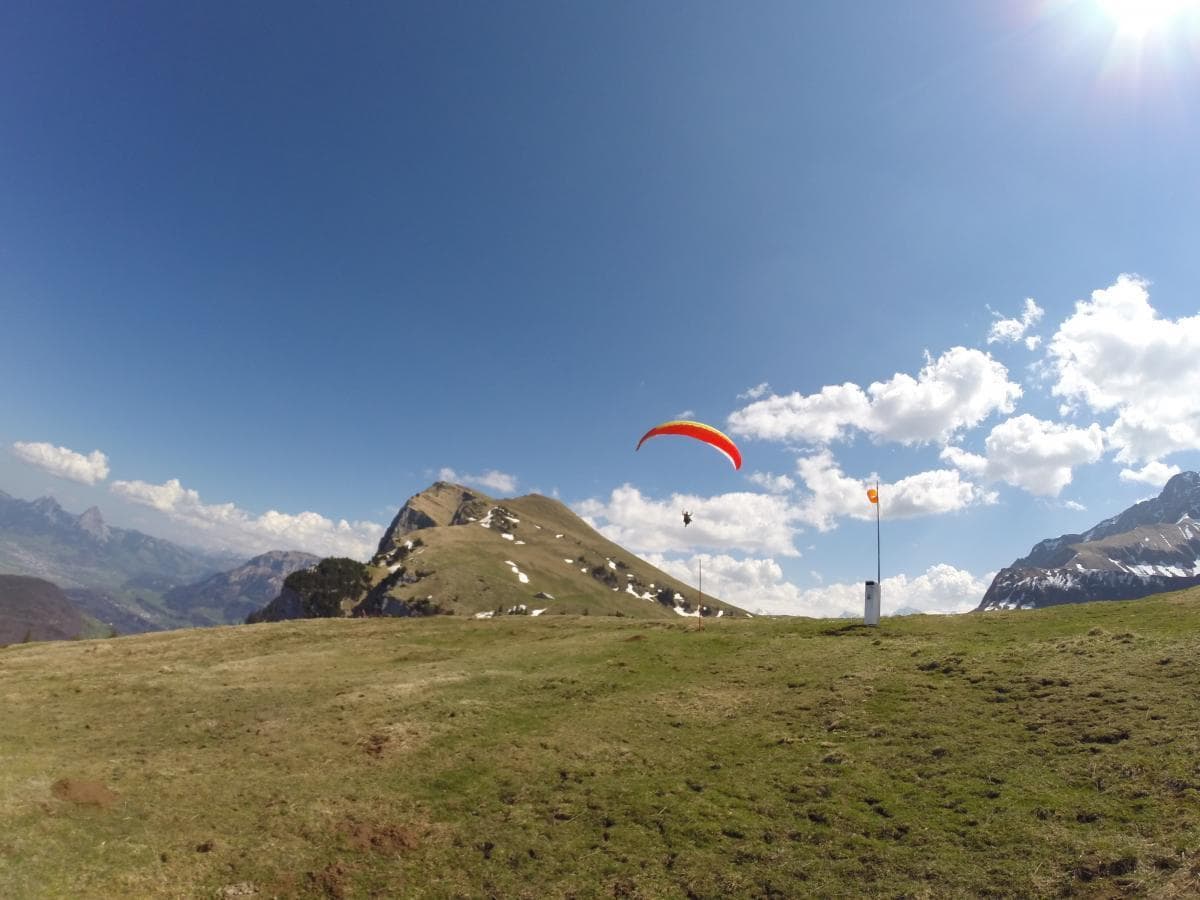 Paraglider launching from alpine ridge with clear blue sky